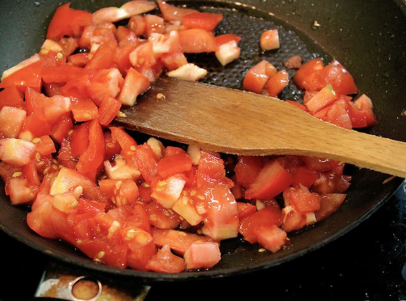 Нарезаем помидор и обжариваем его небольшом огне с маслом.